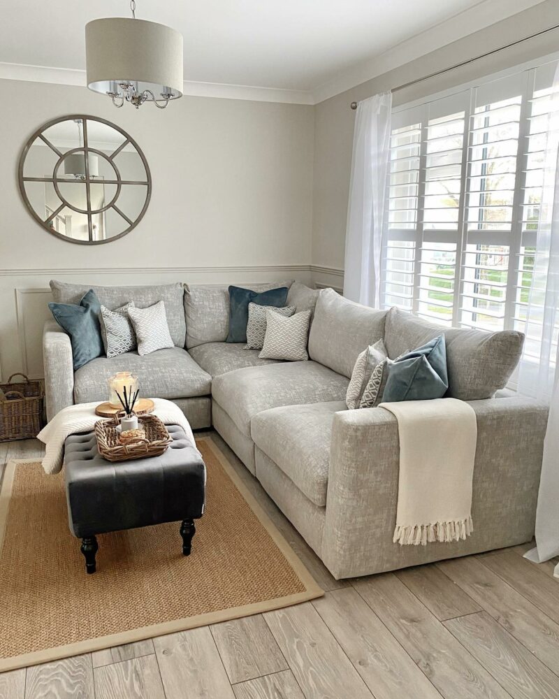 Grey Malvern sofa with white and grey accent cusions. Dark grey velvet footstool with a defusor on top