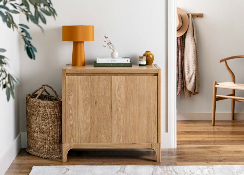 A sideboard-hallway furniture-small wooden sideboard with mustard lamp and books on top